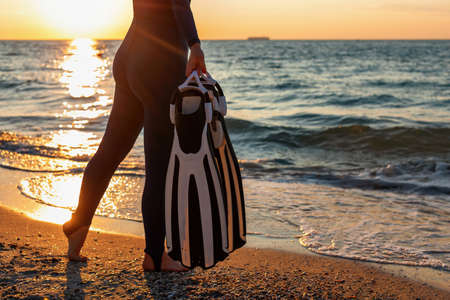 Diver girl in a wetsuit holds flippers in her hands.の写真素材
