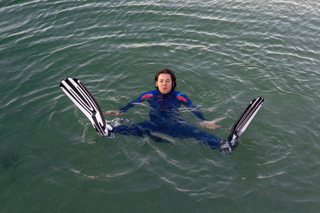 Beach vacation fun woman wearing a wetsuit and flippers making a goofy face while swimming in ocean...