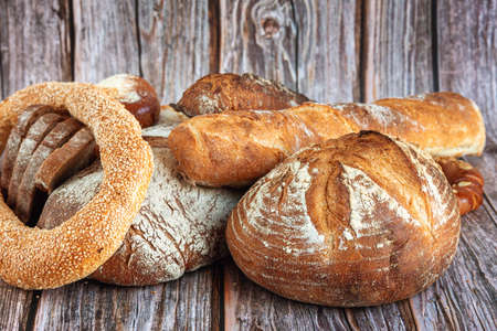Close-up of assortment of baked bread on wooden table backgroundの写真素材
