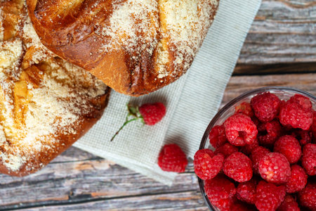 Close up of sweet buns with fresh raspberry on wooden table