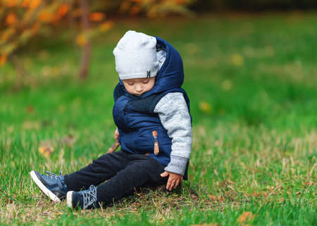 A small child falls asleep sitting in the grassの写真素材