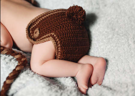 Funny knitted pants with a ponytail on a baby. Little feet of a newborn child.の写真素材