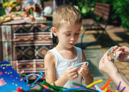 Adorable kid creating toys with chenille sticks. Process of kid crafts. Early education