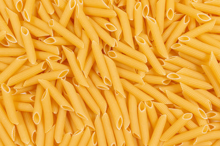 Raw penne pasta background. Close up of uncooked penne pasta. Top view