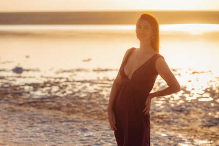 Beautiful caucasian girl outdoor. Portrait of playful woman against sea sunset. Pretty red-haired girl wearing summer dressの写真素材