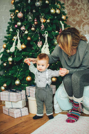 Adorable mother and child son having a good time together near Christmas decorated tree and present boxes. Christmas miracles. Happy New Yearの写真素材