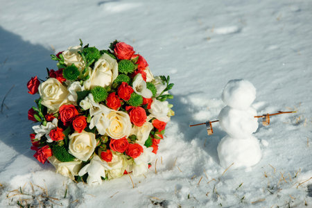 White and red rose wedding bouquet in the snow and wedding rings on a snowman. Winter weddingの写真素材