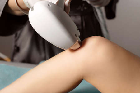 Close up of unrecognizable beautician removing her customer's leg hair. Laser epilation and cosmetology. Hair removal cosmetology procedure. Smooth Skin.の写真素材