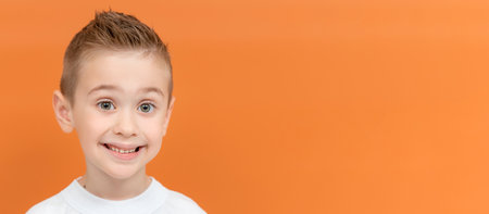 Happy cute preschooler kid in casual clothes on color background. Studio portrait of five year old boy. Banner, copy spaceの写真素材