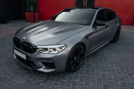 Ukraine, Odessa - July 8, 2021: A matte grey colored and black rimmed custom BMW M5 on the empty parkingのeditorial素材