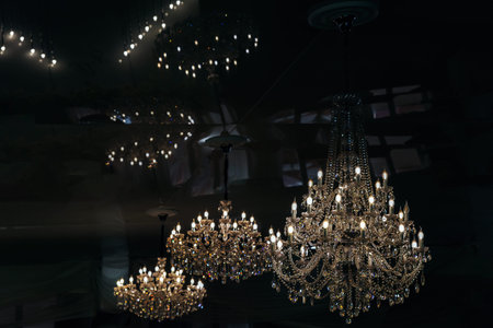 Raw of lighting crystal chandelier in baroque style on a dark background. Ceiling lamps, reflection...