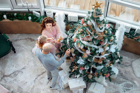 Top view of beatiful Caucasian family decorating a Christmas tree for holiday. High angle view of parents with daughter decorating home. Happy family preparing for Christmas or New Year.の写真素材