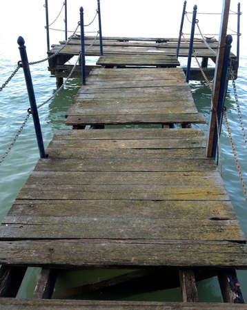 Remains of an old wooden pier with broken boards and rusty iron railingsの写真素材
