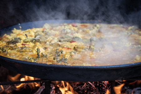 A large paella cooking over a fire with a smokey backgroundの写真素材