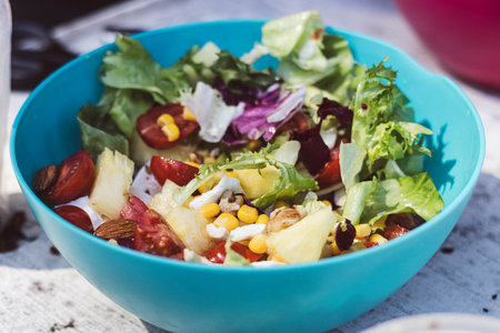 This colorful salad features fresh greens, tomatoes, corn, nuts, and pineapple.の写真素材