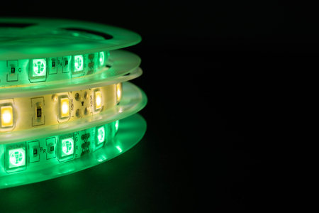 Close-up of LED strip reels glowing green and warm whiteの写真素材