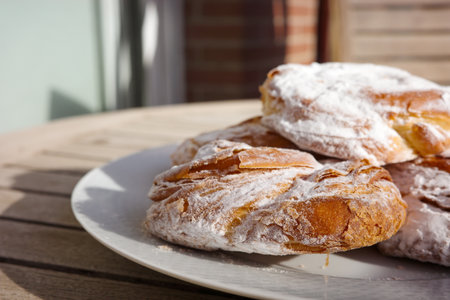 Traditional Spanish ensaimadas with powdered sugar on a plateの写真素材