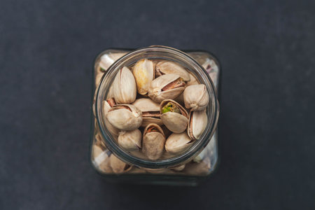 Pistachios in a glass jar on dark backgroundの写真素材