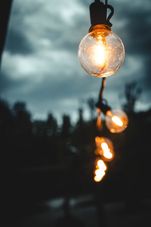 Outdoor string lights glowing at dusk with warm ambianceの写真素材