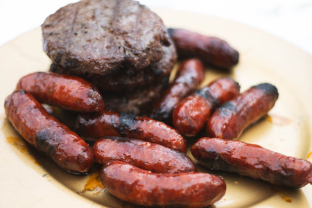 Grilled chorizos and hamburgers served on rustic plateの写真素材
