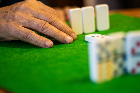 Senior Hand Playing Dominoes on Green Tableの写真素材