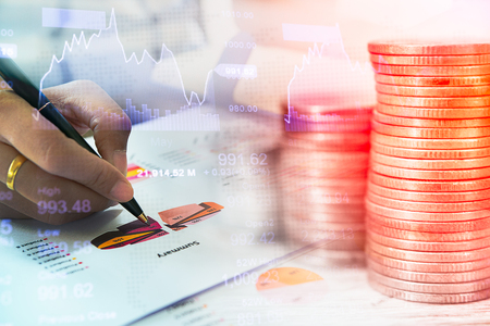 Businessman check seriously analyzes a financial reports. Stack of coins and a hand holding is examining a technical chart of financial instrument. Concept business financeの写真素材