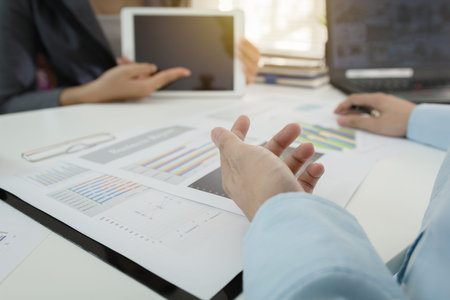 Investor executive discussing plan financial graph data on office table with laptop and tablet,...