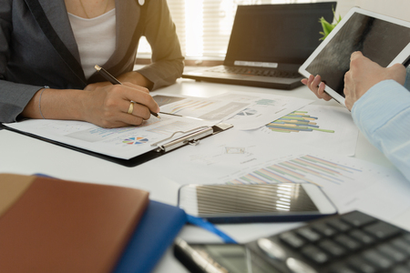 Businessman with finger touching screen of a digital tablet at office on table with document graph data, Businesswoman calculate about cost, Finance managers task, Concept finance investmentの写真素材