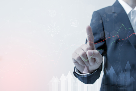Investment Leadership and business innovation and technology concept : Hand of Businessman touching the investment graph network with arrow pointing up abstractの写真素材