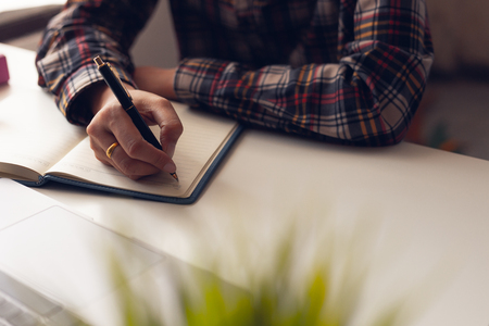 The man is writing a message in the book on table.の写真素材