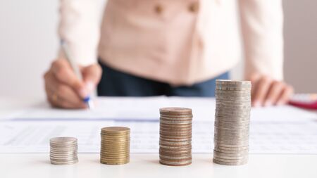Concept growth investment and saving growth stacking coin money with businessman calculate and analysis or financial costsの写真素材