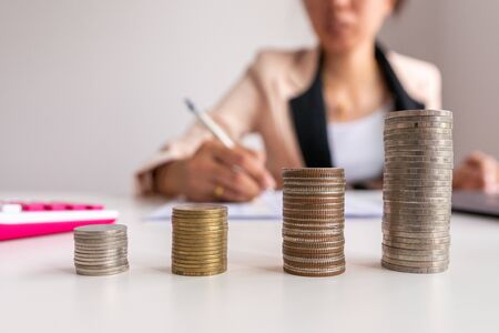 Concept growth investment and saving growth stacking coin money with businessman calculate and analysis or financial costsの写真素材