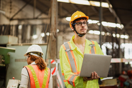 Concept industrial Man engineer using digital laptop working with blur factory background. Engineer...