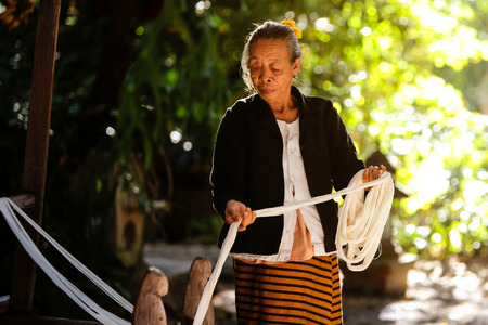 NOVEMBER 16, 2013 - CHIANGMAI THAILAND : Elderly women pulling silk thread from the silkworm in the traditional style.のeditorial素材