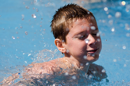 Portrait of a boy in a spray of waterの写真素材