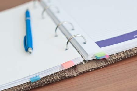 Beige personal organizer and pen on office deskの写真素材