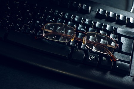 glasses on a black computer keyboard and office desk
の写真素材