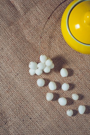 Yellow sugar bowl on a table with white balls.の写真素材