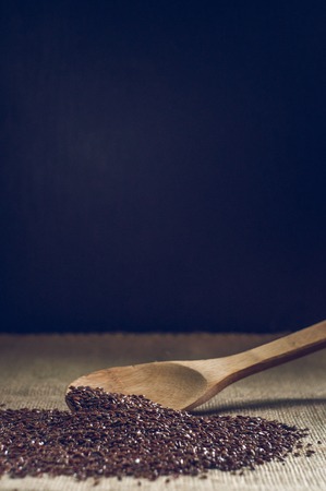 flax seeds with a wooden spoon on burlap background.の写真素材