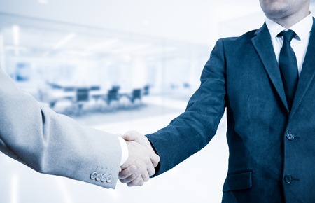 Handshake businessmen in the office background.の写真素材