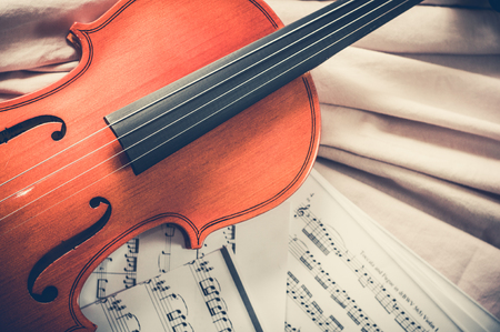 Old violin lying on the sheet of music, music concept.の写真素材