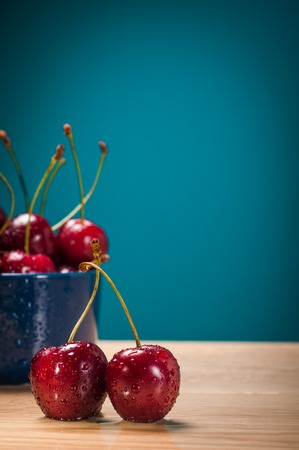 Cherries on wooden table with water drops macro background.の写真素材