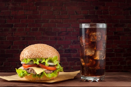Delicious cheeseburger with salad ingredients on a grilled beef patty on a rustic wooden table with copyspace.の写真素材