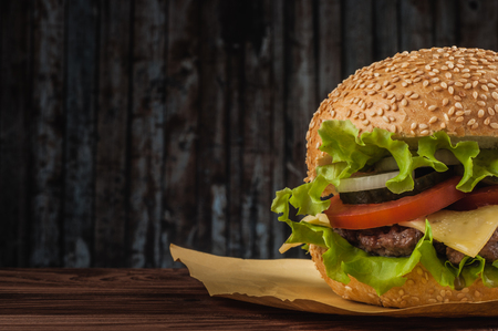 Delicious cheeseburger with salad ingredients on a grilled beef patty on a rustic wooden table with copyspace.の写真素材
