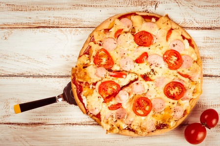 Hot pizza slice with melting cheese on a rustic wooden table.の写真素材