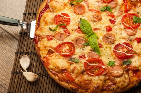 Hot pizza slice with melting cheese on a rustic wooden table.の写真素材