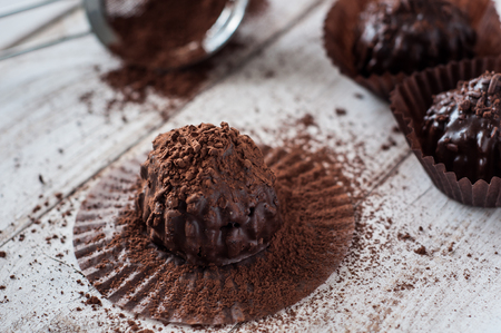 Chocolate chip muffin in brown wax paper. Unwrapped. Cocoa powder in the background.の写真素材