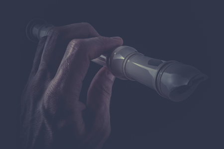 Classic musical instrument flute in hand on black background.の写真素材
