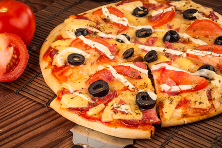 Hot pizza slice with melting cheese on a rustic wooden table.の写真素材