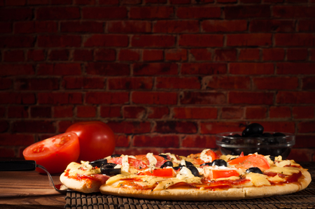 Hot pizza slice with melting cheese on a rustic wooden tableの写真素材